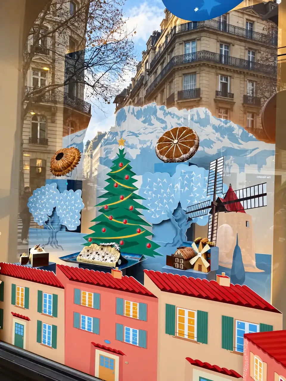 Vitrine de Noël Lenôtre « Un Noël en Provence » : village provençal, montagnes enneigées et sapin en impression découpée sur le vitrage