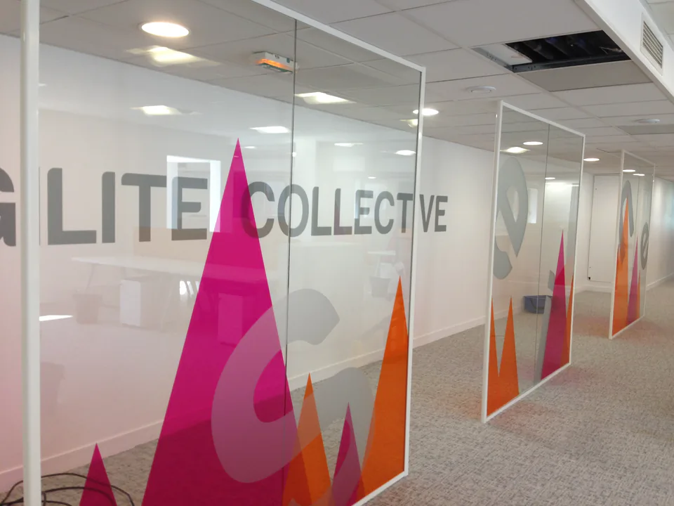 Cloisons vitrées de bureaux à La Défense habillées de montagnes roses et orange en film décoratif, avec le nom de l'entreprise en dépoli